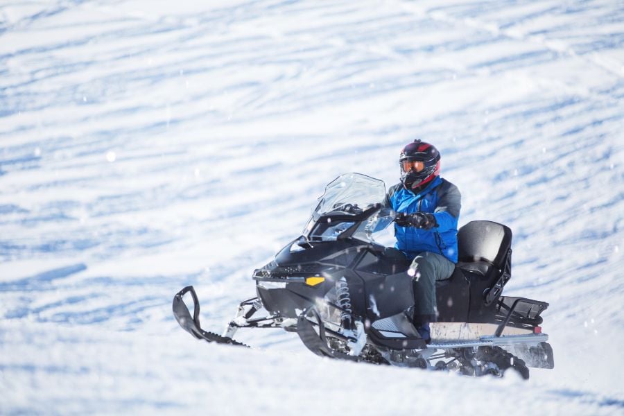 A snowmobiler climbs a snowy Breckenridge slope on a clear winter morning.