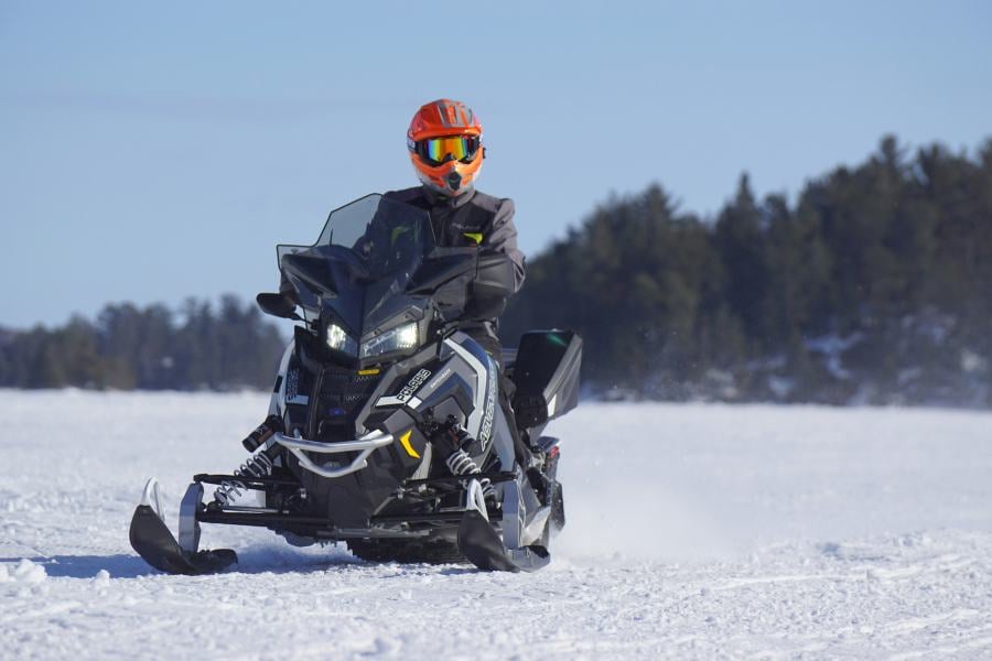 A rider speeds across frozen ground on a powerful snowmobile.