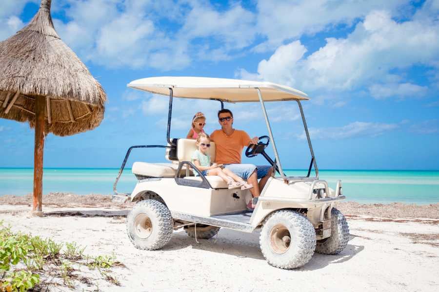 Young father with two small children driving a golf cart.