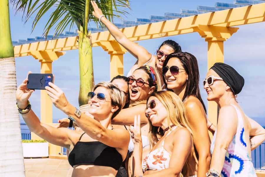 Friends posing for a fun beach selfie under sunny skies.