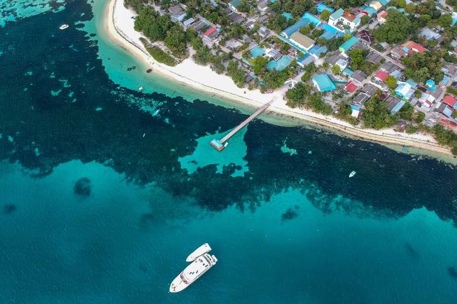 A scenic aerial shot of a coastal town with clear water and boats docked nearby.