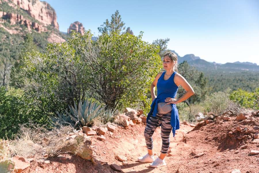 A woman rests on a rocky trail, catching her breath during a sunny hike.