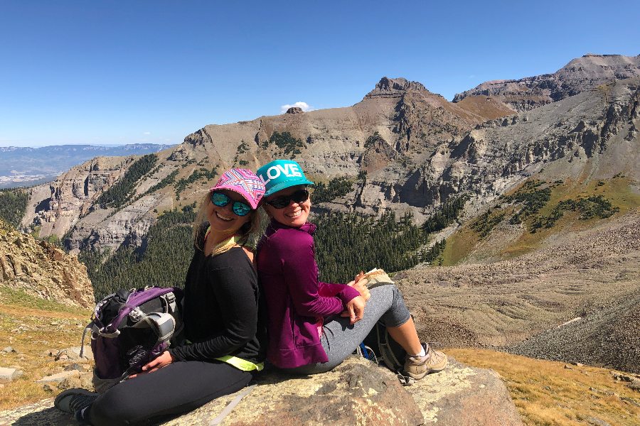Two women sitting in top of mountain