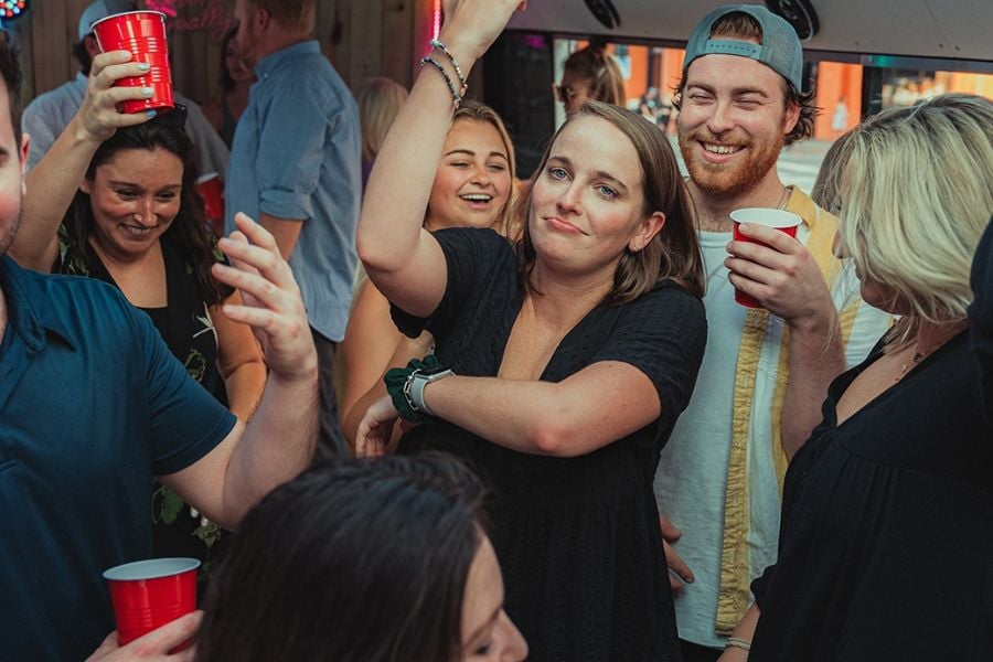 People laugh and dance at a fun party with red cups and happy faces.