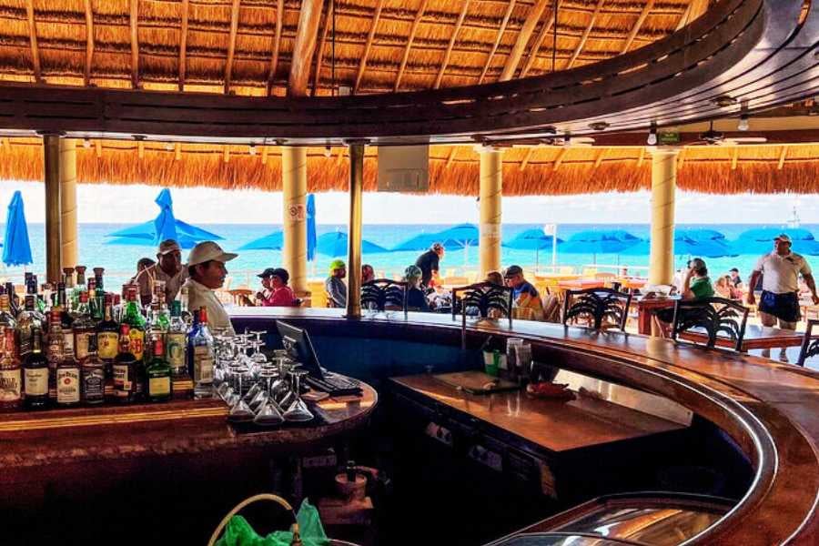 A cozy, thatched-roof bar with colorful drinks and ocean views makes for the ultimate beachside hangout.