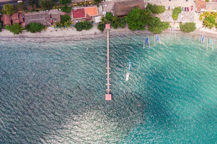 A scenic pier stretches over sparkling turquoise waters, connecting a vibrant shoreline to the open sea.