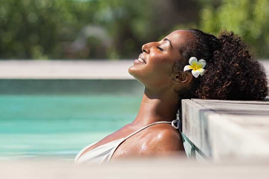 Pure bliss—basking under the sun by the pool with a fresh flower tucked in her hair.