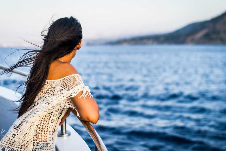 A woman standing on a boat, her hair blowing in the wind, enjoying the open sea view.