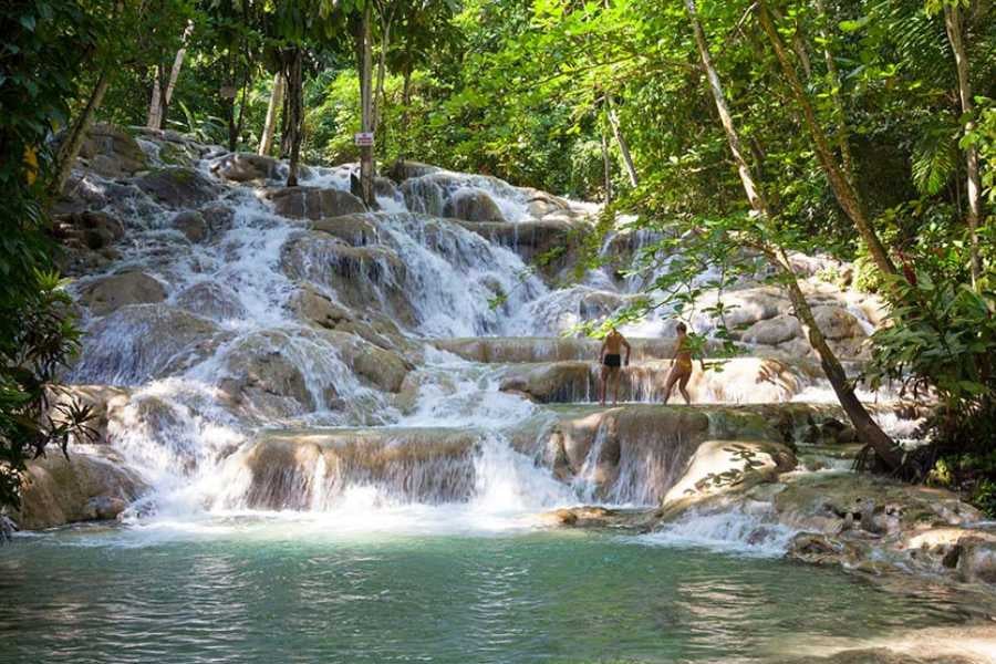 Staggered waterfalls cascading over natural limestone steps, inviting exploration amidst vibrant greenery.