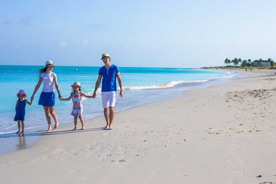 A family is walking on the white sand on the beach