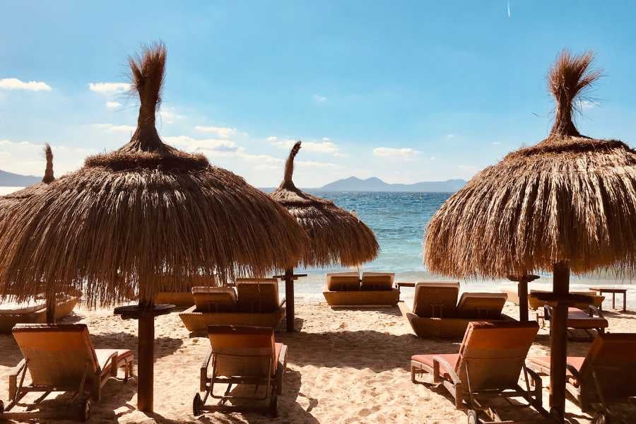 Relaxing loungers with straw palapas and ocean views.