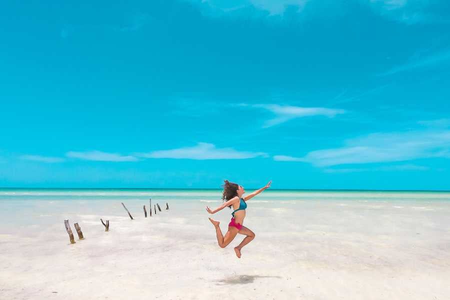 A joyful leap on a pristine beach under a bright blue sky.