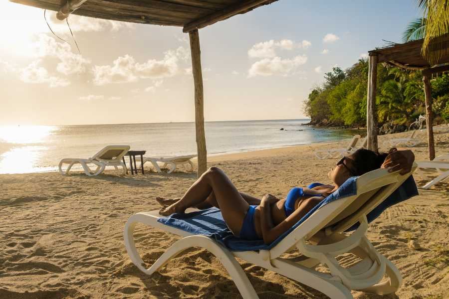 A Women lounging in a chair on the beach, enjoying the sunset and peaceful surroundings.