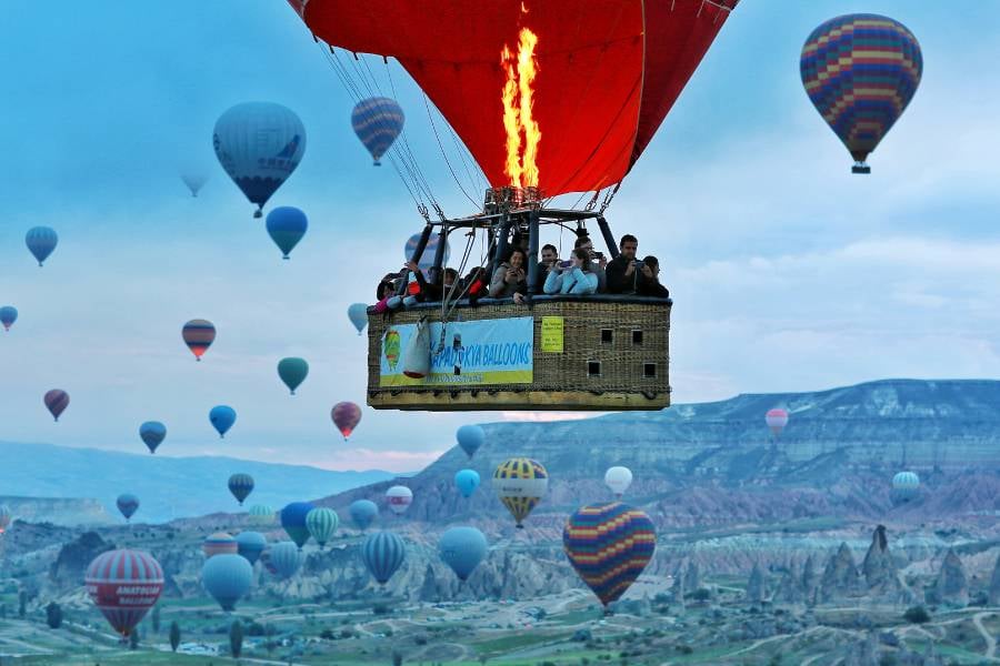 A group of people is riding in a hot air balloon with many others in the sky.