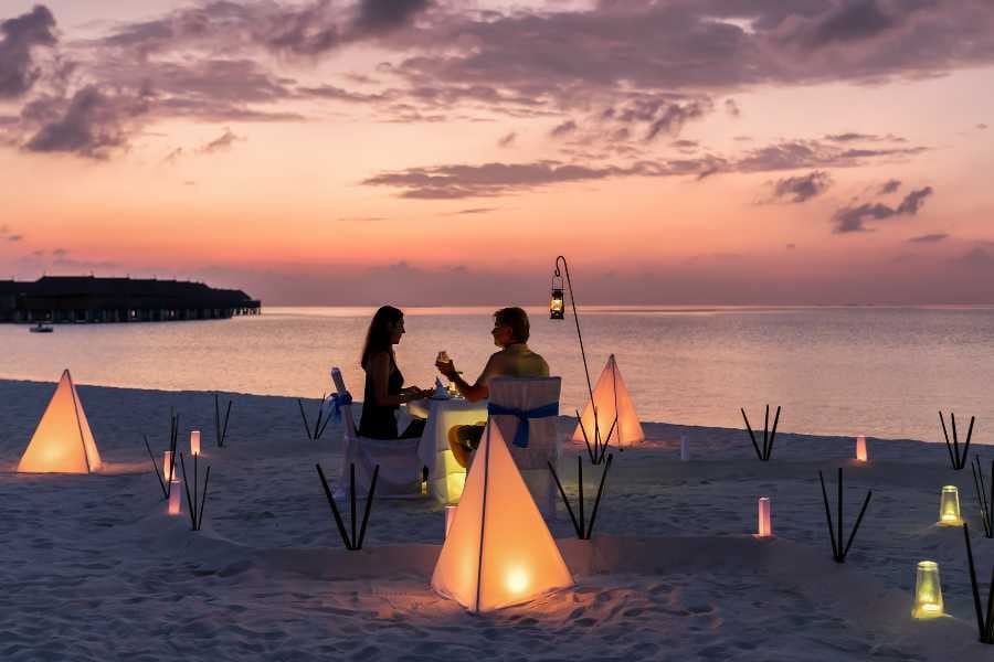 A couple is having dinner in a romantic spot on the beach