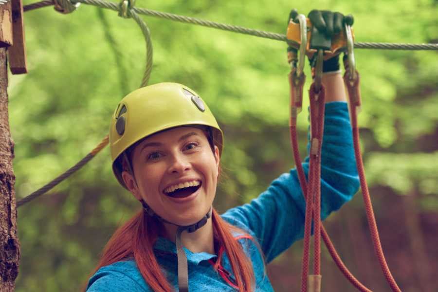 A woman enjoying the thrill of zip-lining through a lush forest.