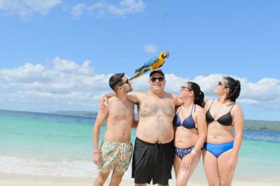 A group of friends enjoying a beach day with a colorful parrot on their shoulder.