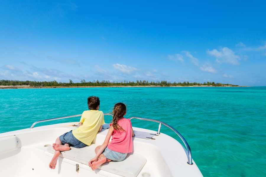 Two children enjoy the turquoise ocean views from a boat, soaking in the serenity of the horizon.