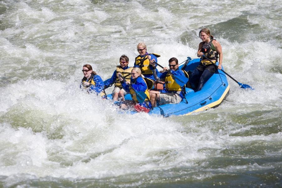 Group powers through crashing rapids with paddles in sync.