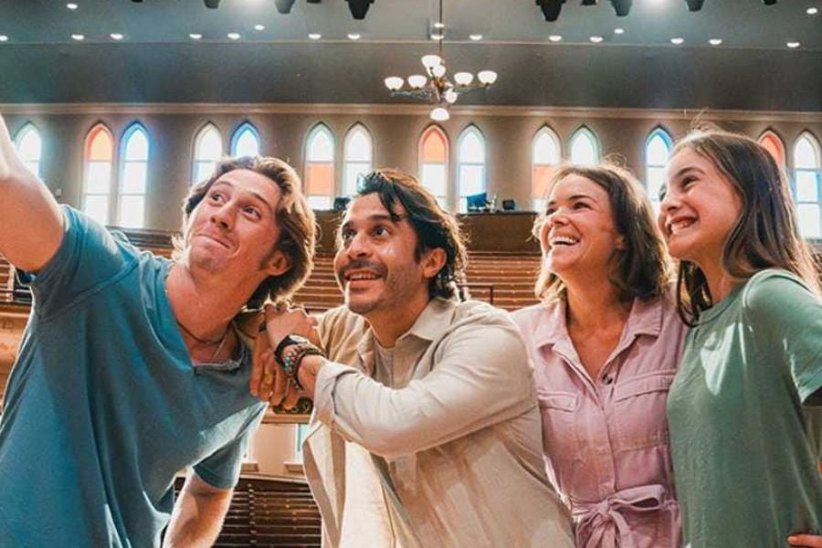 Family taking a selfie inside a beautiful old concert hall with colorful windows.