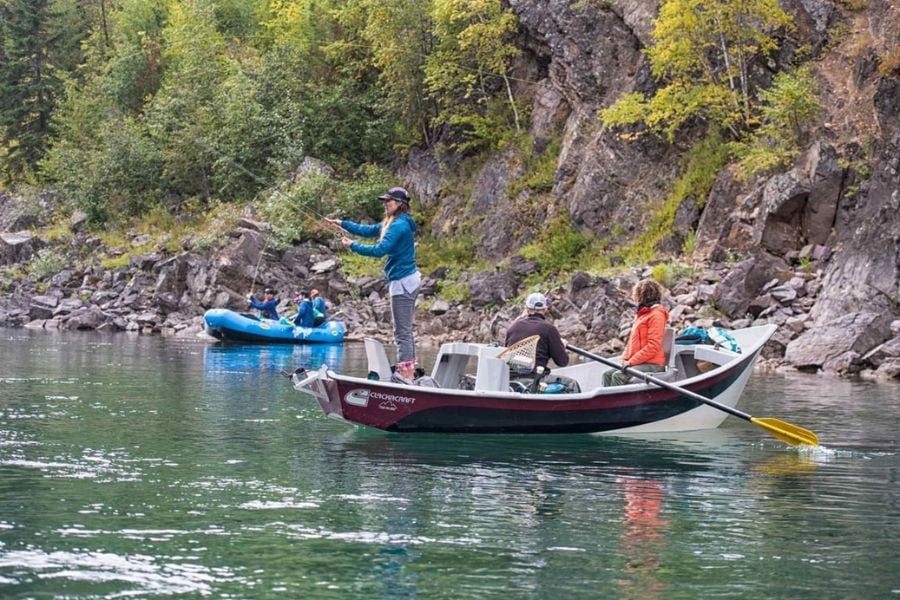 Anglers casting lines from boats in a peaceful canyon with crystal-clear water.