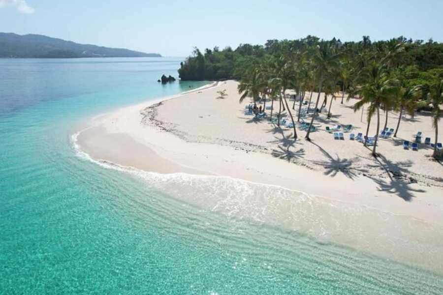 An aerial view of a pristine beach with turquoise waters and palm trees.