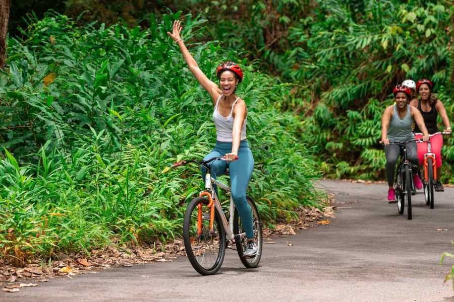 A joyful cyclist waves as she rides along a scenic jungle path with friends.