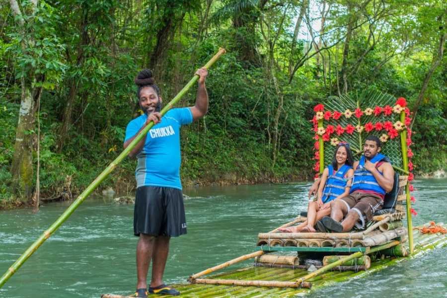 A couple floats down a peaceful river on a decorated bamboo raft, guided by a local expert.