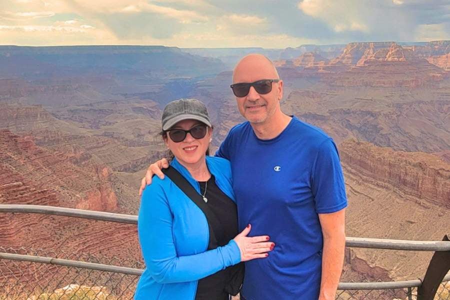 A couple stands in front of a wide, scenic mountain view.