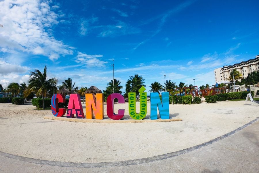 Bright Cancun sign pops under blue skies at the city’s sunny beachfront.