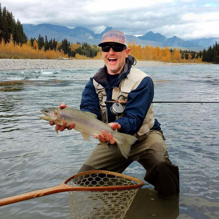 man holding fish in middle fork of flathead river 