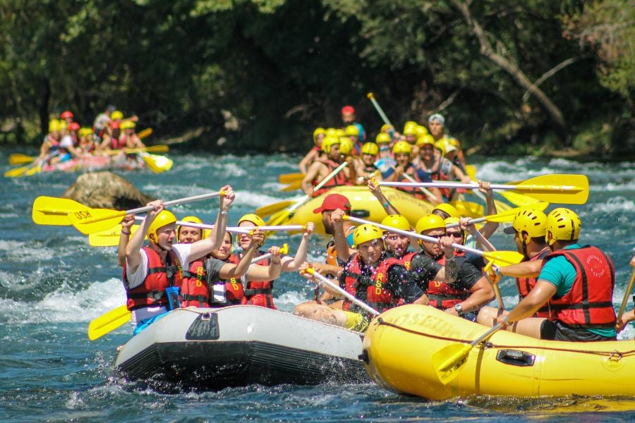 Dozens of rafts race downstream, paddlers cheering with excitement.