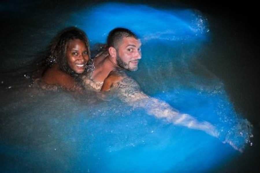 A couple enjoys swimming in bioluminescent waters, lighting up the dark sea.