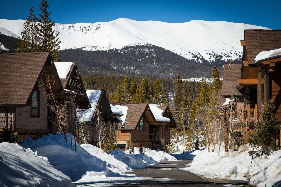 Cozy wooden cabins sitting along a snowy road with Breckenridge mountain views.