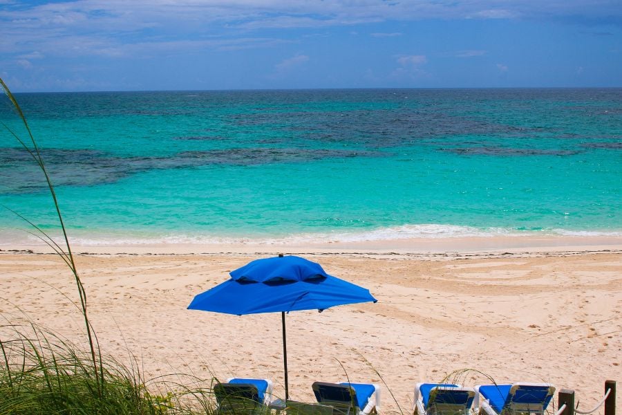 A peaceful beach scene with turquoise water, an empty sand stretch, and a beach umbrella for shade.