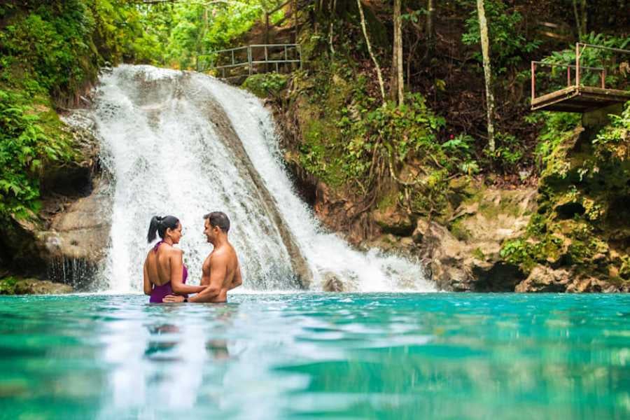 A couple enjoys a romantic moment beneath a stunning waterfall.