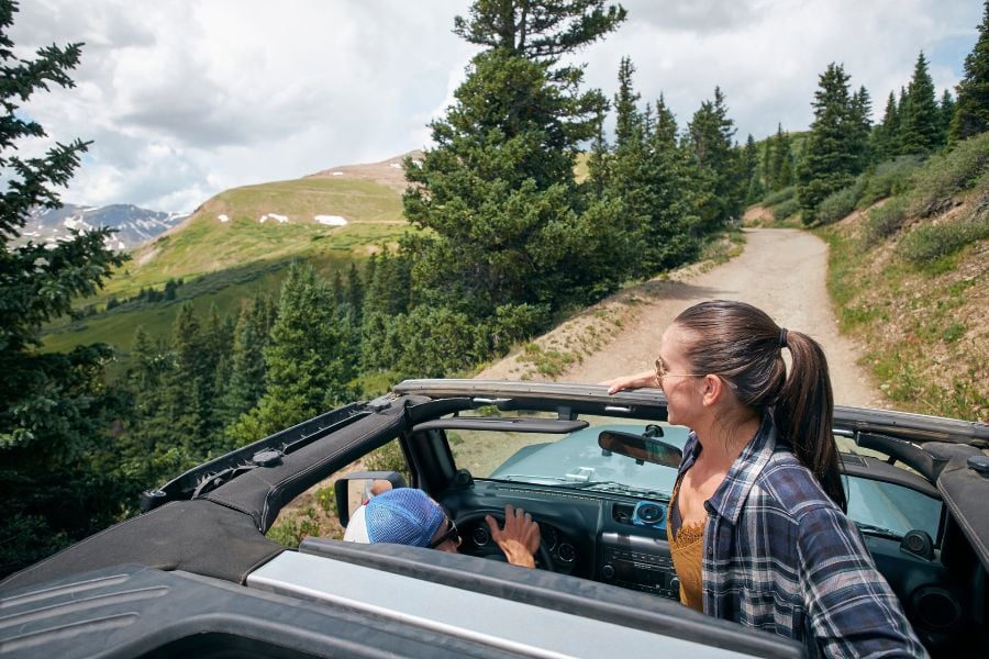 Couple exploring scenic dirt roads through alpine forests in Vail, Colorado by Jeep.