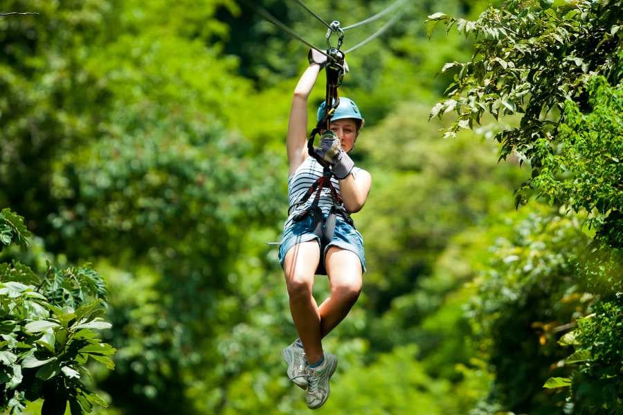 A woman zip-lining through the jungle, feeling the thrill of soaring above the treetops.