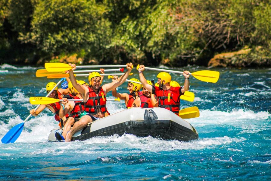A group of friends paddles through rushing water on an exciting whitewater rafting trip.